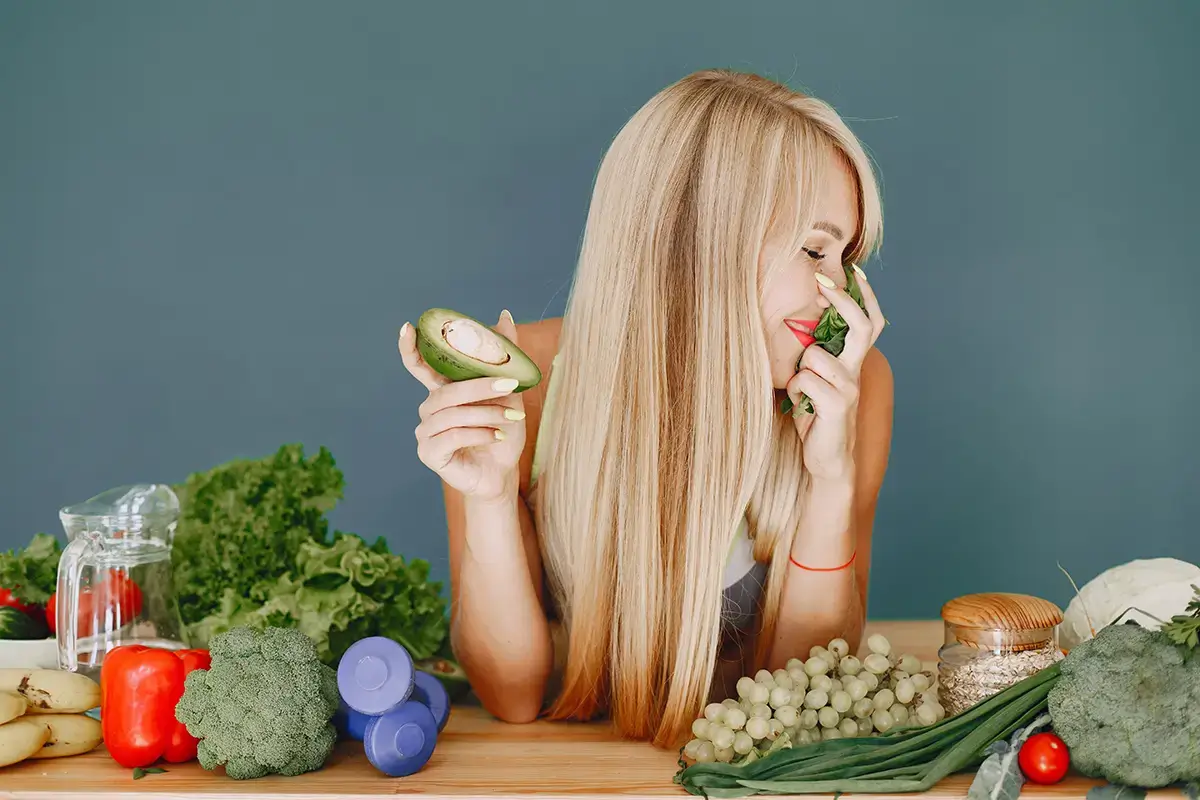 mulher de cabelos loiros longos com um avocado na mão